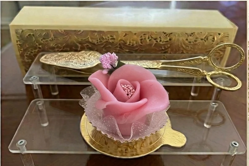 Pâtisserie en forme de rose rose, présentée sur un plateau doré