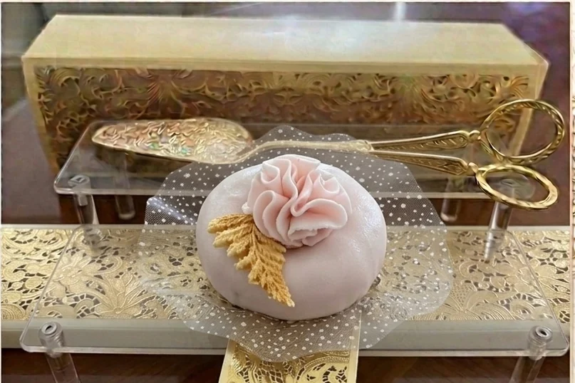 Pâtisserie ronde décorée d’une fleur rose pâle et de détails dorés