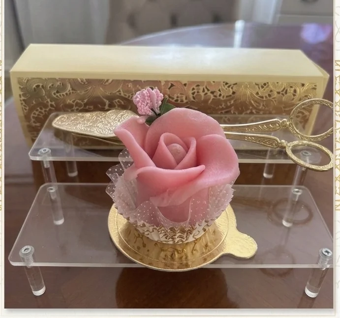 Pâtisserie en forme de rose rose présentée sur son support doré