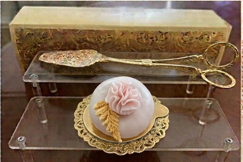 Pâtisserie ronde décorée d’une fleur rose pâle et de détails dorés