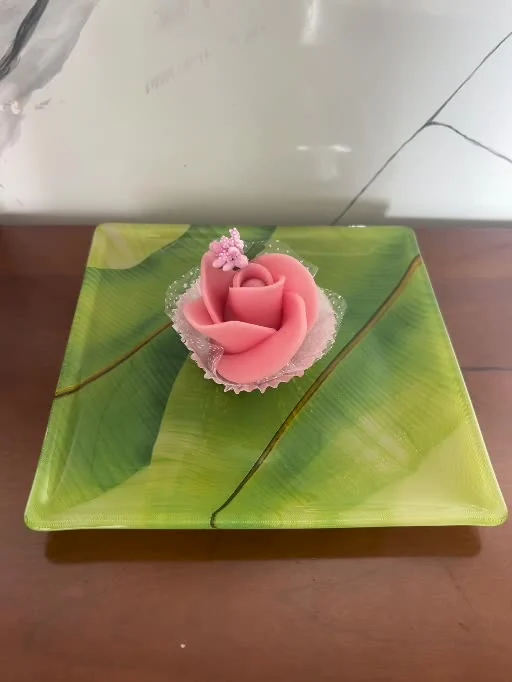 Rose rose en pâte d’amande présentée sur une assiette verte