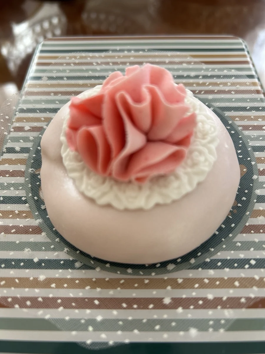Petite pâtisserie ronde surmontée d’une rose en pâte d’amande