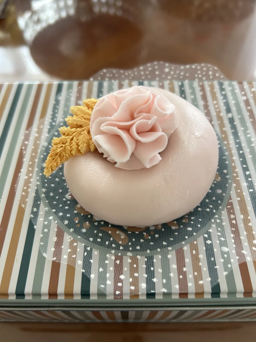 Pâtisserie blanche décorée d’une rose rose et de détails dorés